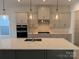 Modern kitchen with gray cabinets, white quartz island, and stainless steel appliances at 7050 Wayfarer Dr # 0085, Charlotte, NC 28269