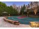A fenced backyard basketball court with stone retaining wall and lush landscaping at 3042 Kings Manor Dr, Weddington, NC 28104