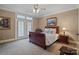 Cozy bedroom features neutral walls, carpet, and a charming sleigh bed next to shuttered french doors at 3042 Kings Manor Dr, Weddington, NC 28104