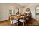 Formal dining room with a wooden table, china cabinet, chandelier, and large arched window at 3042 Kings Manor Dr, Weddington, NC 28104