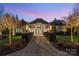 Elegant home with a beautifully landscaped walkway, stunning architecture, and warm exterior lighting at 3042 Kings Manor Dr, Weddington, NC 28104