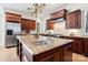 Gourmet kitchen features rich wood cabinets, granite countertops, stainless appliances and an ornate chandelier at 3042 Kings Manor Dr, Weddington, NC 28104