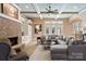 A cozy living room with stone fireplace, built-in shelving, and a gray sectional sofa beneath the coffered ceiling at 3042 Kings Manor Dr, Weddington, NC 28104