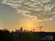 Sunrise view of the city skyline, with modern condos and a construction crane silhouetted against the bright sun at 2338 Yadkin Ave # 505, Charlotte, NC 28205