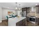 Modern kitchen with island, opens to dining area with teal chairs at 1814 Archdale Dr, Charlotte, NC 28210