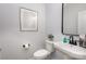 Small bathroom with white toilet and sink, black fixtures, and framed art at 3016 Sadler Woods Ln, Charlotte, NC 28214