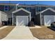 Exterior view of gray townhomes, white garages, and neat front lawns with clear, blue skies at 5552 Stafford Rd # 28, Charlotte, NC 28215