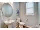 Elegant powder room featuring a pedestal sink, round mirror, and natural light at 9831 Quercus Ln, Huntersville, NC 28078