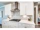 A kitchen with stainless steel vent hood, white cabinets, white countertops, and tile backsplash at 9831 Quercus Ln, Huntersville, NC 28078