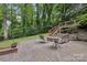 Stone patio features a fire pit, seating and a stairway leading up to the deck, surrounded by greenery at 132 30Th Nw Ave, Hickory, NC 28601