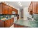 Galley-style kitchen with wood cabinets, green countertops, and white appliances at 5550 Monticello Nw Dr, Concord, NC 28027