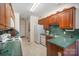 Galley-style kitchen with wood cabinets, green countertops, and white appliances at 5550 Monticello Nw Dr, Concord, NC 28027