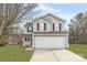 Two-story home featuring a gray exterior, white garage door, well-manicured lawn, and mature trees at 8702 Wood Sorrel Ct, Matthews, NC 28105