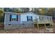 Gray mobile home with a deck, brick base, and wooded setting at 114 River Ridge Ln, Hickory, NC 28601