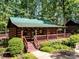 Quaint log cabin with green roof and wrap-around porch at 1410 Tranquility Blvd, Lancaster, SC 29720