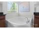 Soaking tub with tile surround in a bright bathroom at 17527 Austins Creek Dr, Charlotte, NC 28278