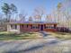 Brick ranch house with metal roof, landscaping, and gravel driveway at 44743 Fish Camp Rd, New London, NC 28127