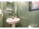 Small powder room with pedestal sink, oval mirror, and green walls at 8044 Sapwood Ct, Matthews, NC 28104