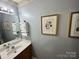 Simple and elegant half-bathroom with a floating shelf, framed botanical prints, and wood vanity at 1668 Sandpiper Dr, Rock Hill, SC 29732