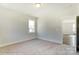 Well-lit bedroom with neutral walls and carpet, featuring a window and access to another room at 3237 Mcharney Dr # 29, Harrisburg, NC 28075