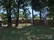 Scenic view of backyard featuring a grassy lawn, several trees, and a wood fence at 9624 Langston Mill Rd, Charlotte, NC 28216