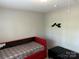 Small bedroom with a red bed and a black ottoman at 9624 Langston Mill Rd, Charlotte, NC 28216