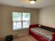 A small bedroom with a red twin bed is situated next to a window at 9624 Langston Mill Rd, Charlotte, NC 28216