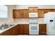 Kitchen with wood cabinets, white appliances, and double sink at 13441 Calloway Glen Dr, Charlotte, NC 28273