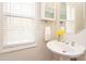 Small powder room with pedestal sink, window, and decorative flowers at 5023 Ancestry Cir, Matthews, NC 28104