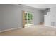 Bright living room featuring neutral carpet and walls, with large sliding glass doors leading to the outside at 7019 Walnut Ridge Ct, Charlotte, NC 28217