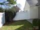 White lattice fence borders a backyard featuring a manicured bush, grass and trees at 8620 Robinson Forest Dr, Charlotte, NC 28277