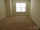 Empty bedroom showcasing neutral walls and carpet flooring with a bright window at 8620 Robinson Forest Dr, Charlotte, NC 28277