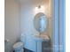 Stylish powder room with pedestal sink and round mirror at 1540 Striped Bass Ln, Clover, SC 29710