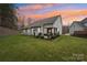 Serene backyard view at sunset, featuring a patio and grill, backing up to wooded area at 16341 Autumn Cove Ln, Huntersville, NC 28078