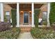 Brick front porch with columns, a dark door, and lush landscaping at 16341 Autumn Cove Ln, Huntersville, NC 28078