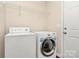 Bright laundry room with washer, dryer, overhead shelving, and exterior access door at 208 Lakewood Ave, Charlotte, NC 28208