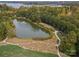 Aerial view of a tranquil pond in a community setting, surrounded by lush trees and landscaping at 211 Harbour Place Dr, Davidson, NC 28036