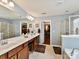 Main bathroom with dual sink vanity, soaking tub, and glass-enclosed shower adjacent to walk-in closet at 3020 Sewee Ln, Waxhaw, NC 28173