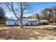 Front view of a ranch home with a large tree and American flag at 5020 Foster Rd, Cleveland, NC 27013