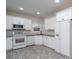 Bright kitchen featuring white cabinets, modern appliances, and stone countertops at 9451 Bonnie Briar Cir, Charlotte, NC 28277