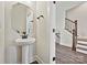 A bathroom with a pedestal sink, octagonal mirror, and view of the stairway at 1227 E 34Th St # Csw0420, Charlotte, NC 28205