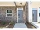Close-up of a modern front door with brick exterior, a small window and concrete walkway at 1227 E 34Th St # Csw0420, Charlotte, NC 28205