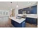 Open-concept kitchen with navy blue cabinets, stainless steel appliances, quartz countertops, a center island, and hardwood floors at 1227 E 34Th St # Csw0420, Charlotte, NC 28205