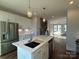 Open floor plan: kitchen with white cabinetry, stainless appliances, and large island leading to staircase to the second level at 1229 E 34Th St # Csw0421, Charlotte, NC 28205
