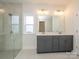 Bright bathroom features double vanity with gray cabinetry and a glass-enclosed shower at 3111 Vermillion Dr, Harrisburg, NC 28075