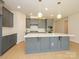 Kitchen featuring gray cabinets, quartz counters, and a large island with a sink and modern fixtures at 3111 Vermillion Dr, Harrisburg, NC 28075