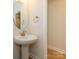 Stylish powder room featuring a pedestal sink, oval mirror, and plank flooring at 3111 Vermillion Dr, Harrisburg, NC 28075