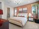 A bedroom with patterned accent wall, a large bed, stylish lighting, and an ensuite bathroom offers a luxurious retreat at 5620 Kingspan Dr, Charlotte, NC 28217