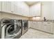 Functional laundry room with modern washer and dryer units, ample cabinet space, and a tiled floor at 9809 Saddle Ave, Waxhaw, NC 28173