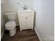 Cozy bathroom featuring a toilet and a clean white sink with white cabinets and modern hardwood flooring at 1608 Carfax Dr, Charlotte, NC 28216